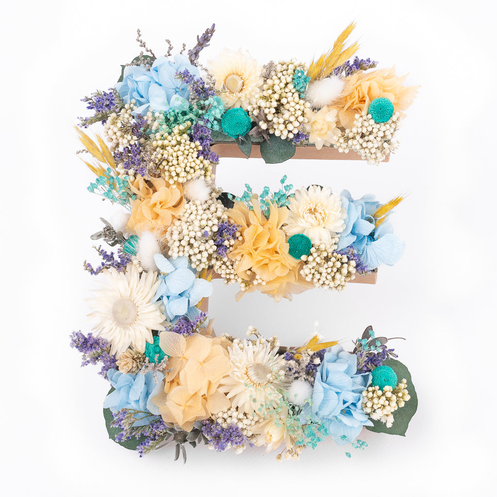 Letra de flores preservadas en tonos azules