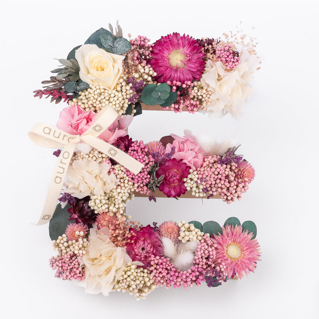 Letra de flores preservadas en tonos rosas