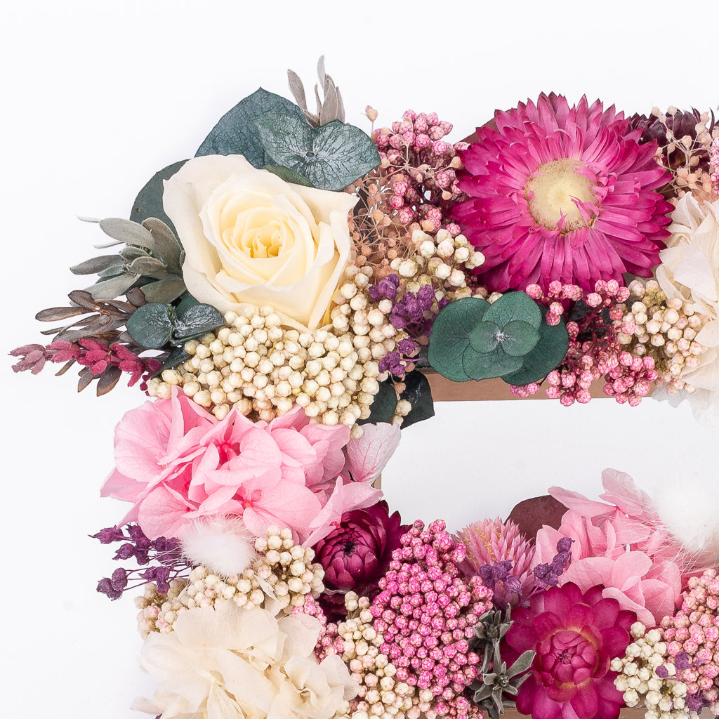 Letra de flores preservadas en tonos rosas