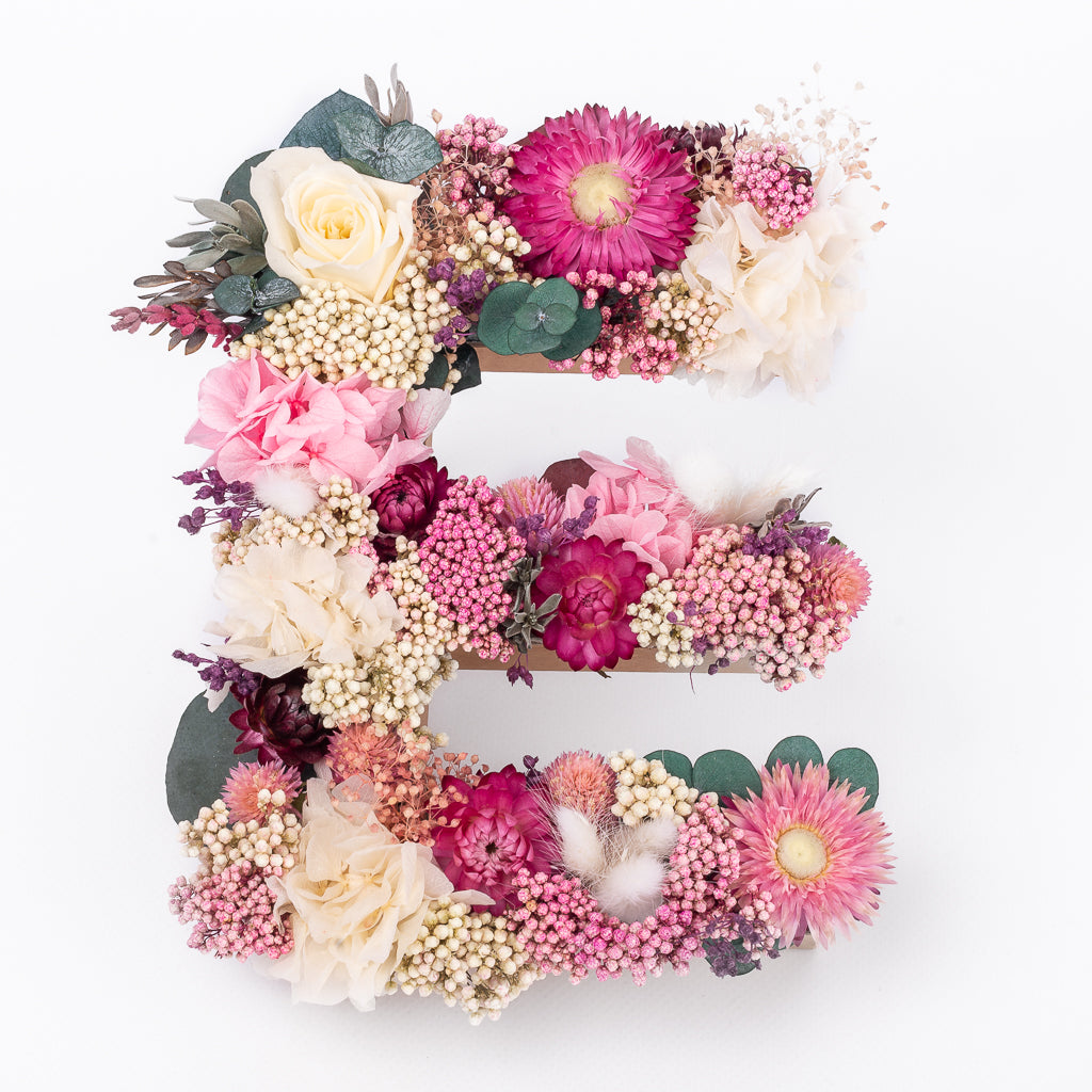 Letra de flores preservadas en tonos rosas