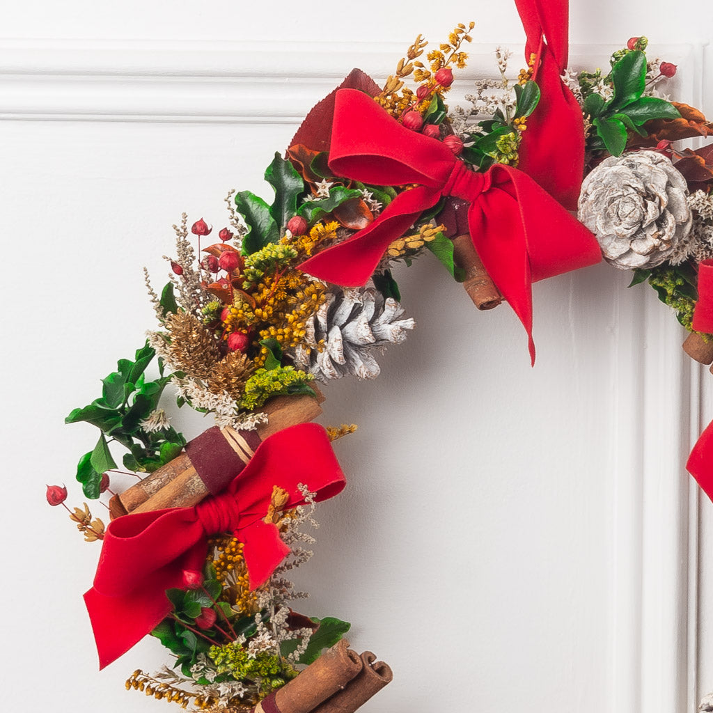 corona de navidad con flores y verdes preservados