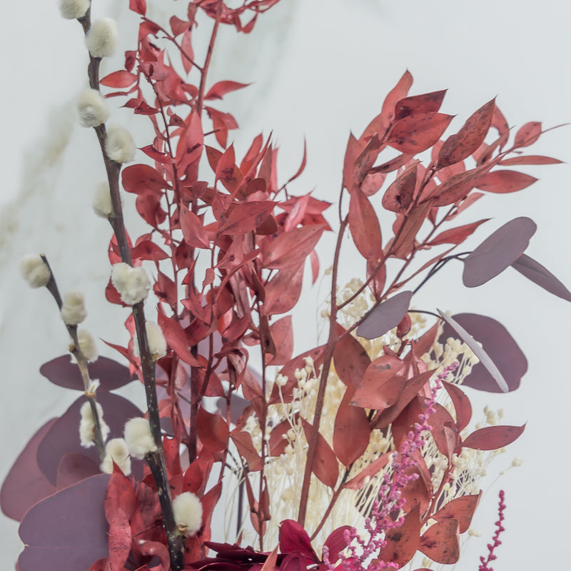 Detalle de ramillete de flores preservadas en tonos granate
