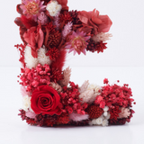 detalle de letra de flores preservadas tonos rojos