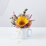 taza con flores preservas y girasol